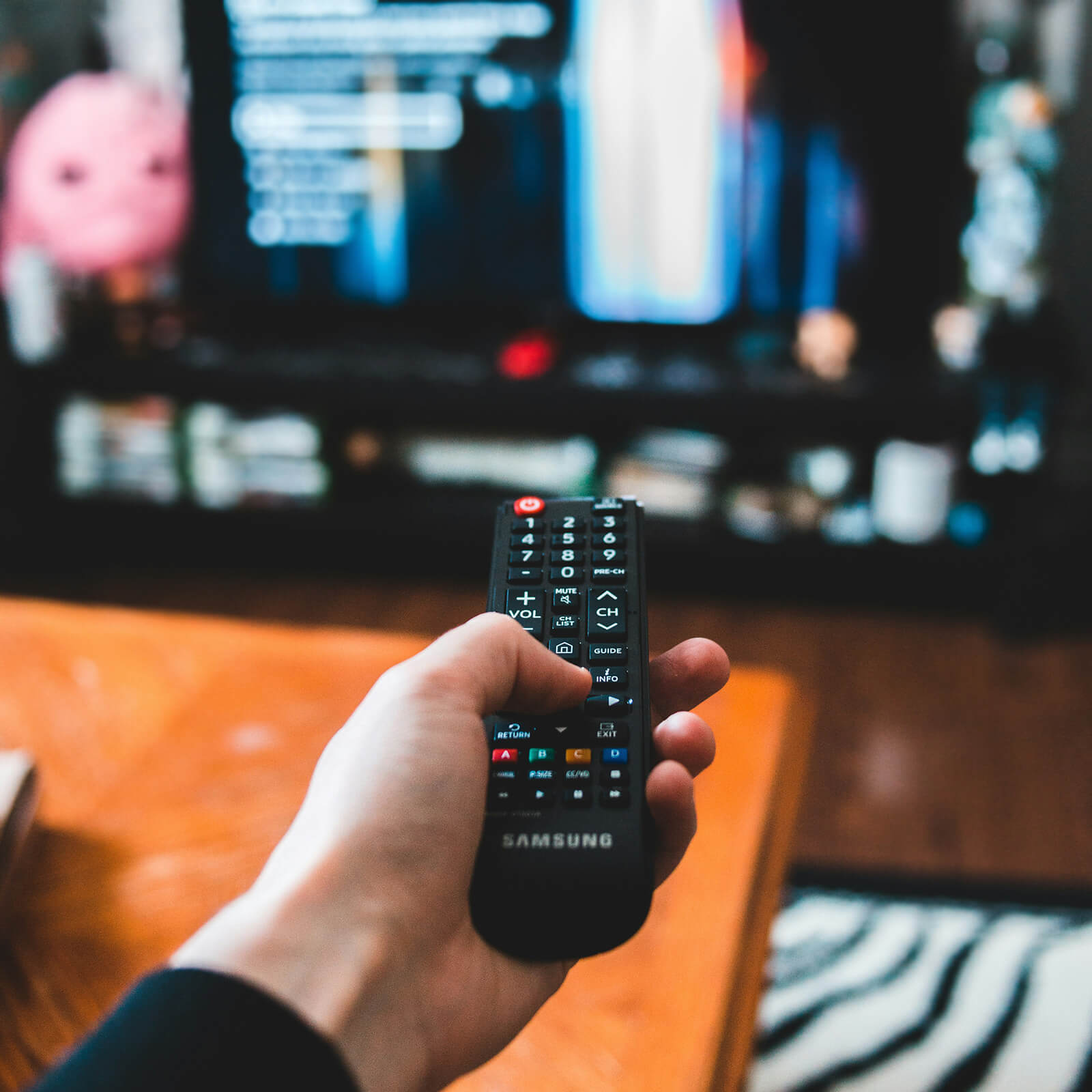 Image of a person's hand pointing a remote control at a television