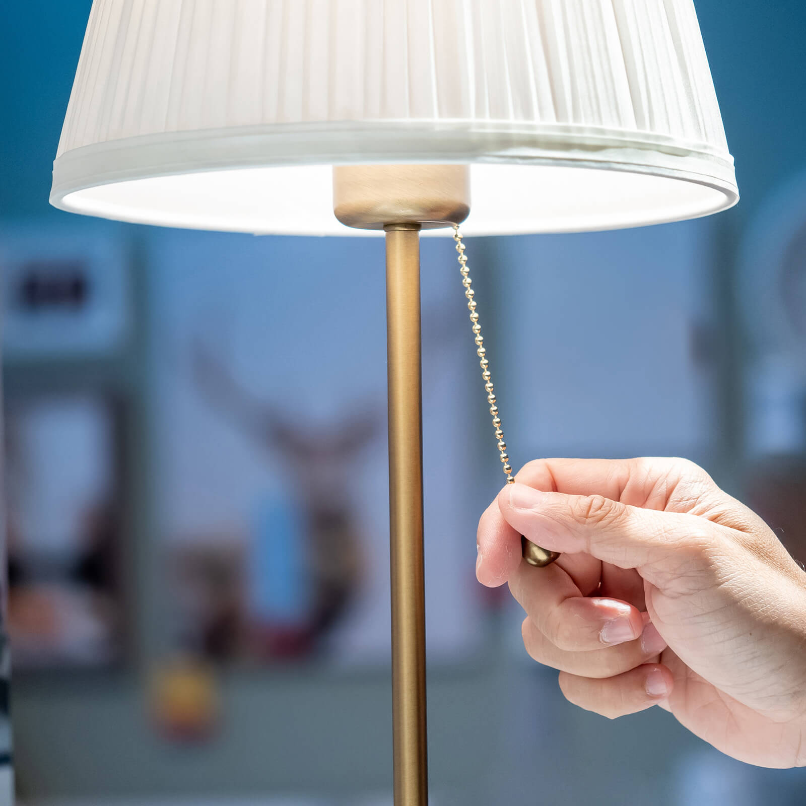 A person pulling a small chain to turn on a table lamp